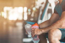 Man holding pre-workout and water bottle